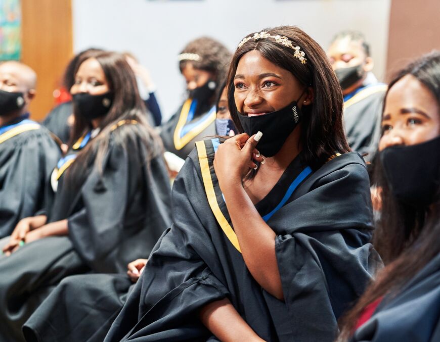 A group of women at the graduation ceremony. One of them smiles into the camera.