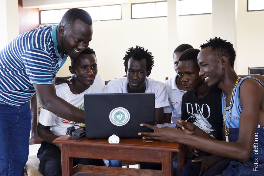 6 pupils looking at a laptop with a Learning Lions sticker